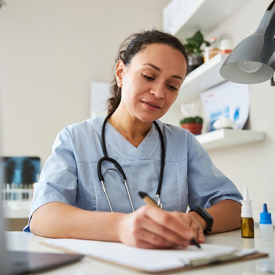Médica escribiendo una receta en su consultorio
