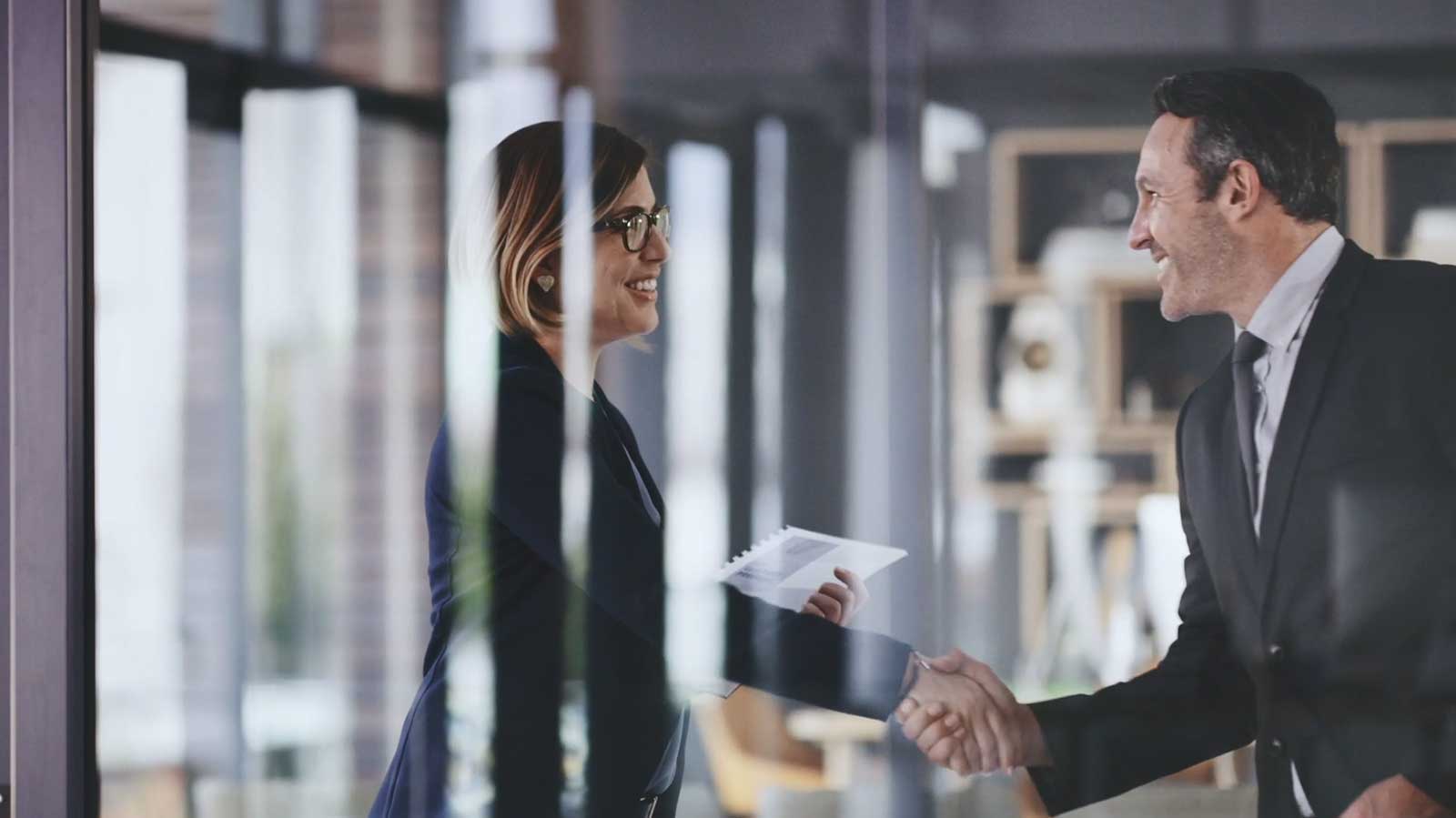 A business woman and business man exchanging a handshake in an office.