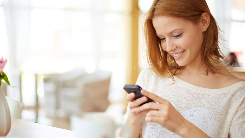 Mujer mirando sonriente su celular