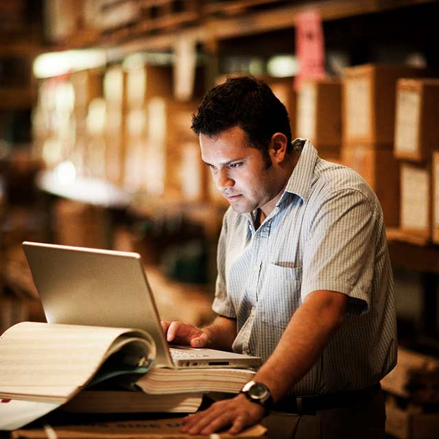 hombre trabajando en laptop dentro de almacen